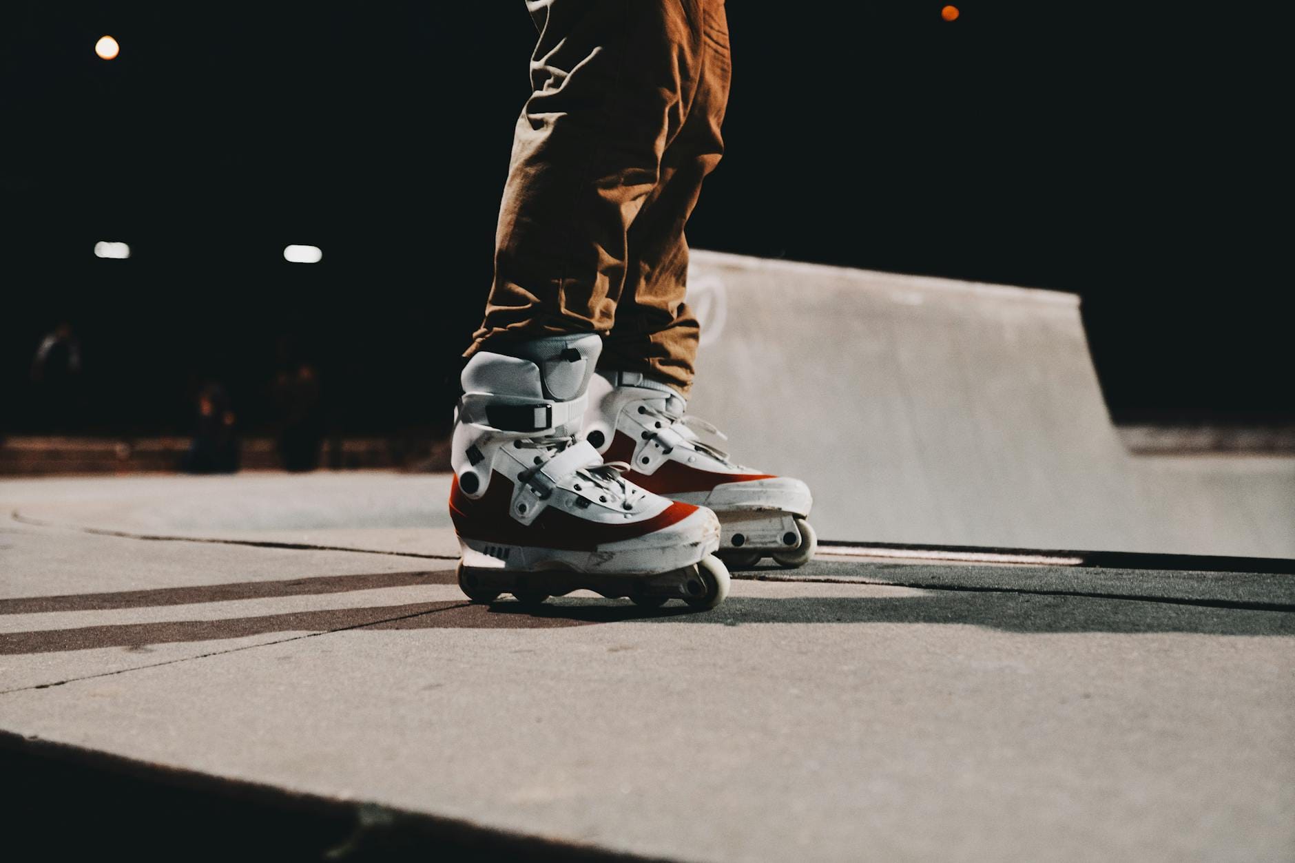 Osoba na rolkach inline na betonowej nawierzchni skateparku nocą