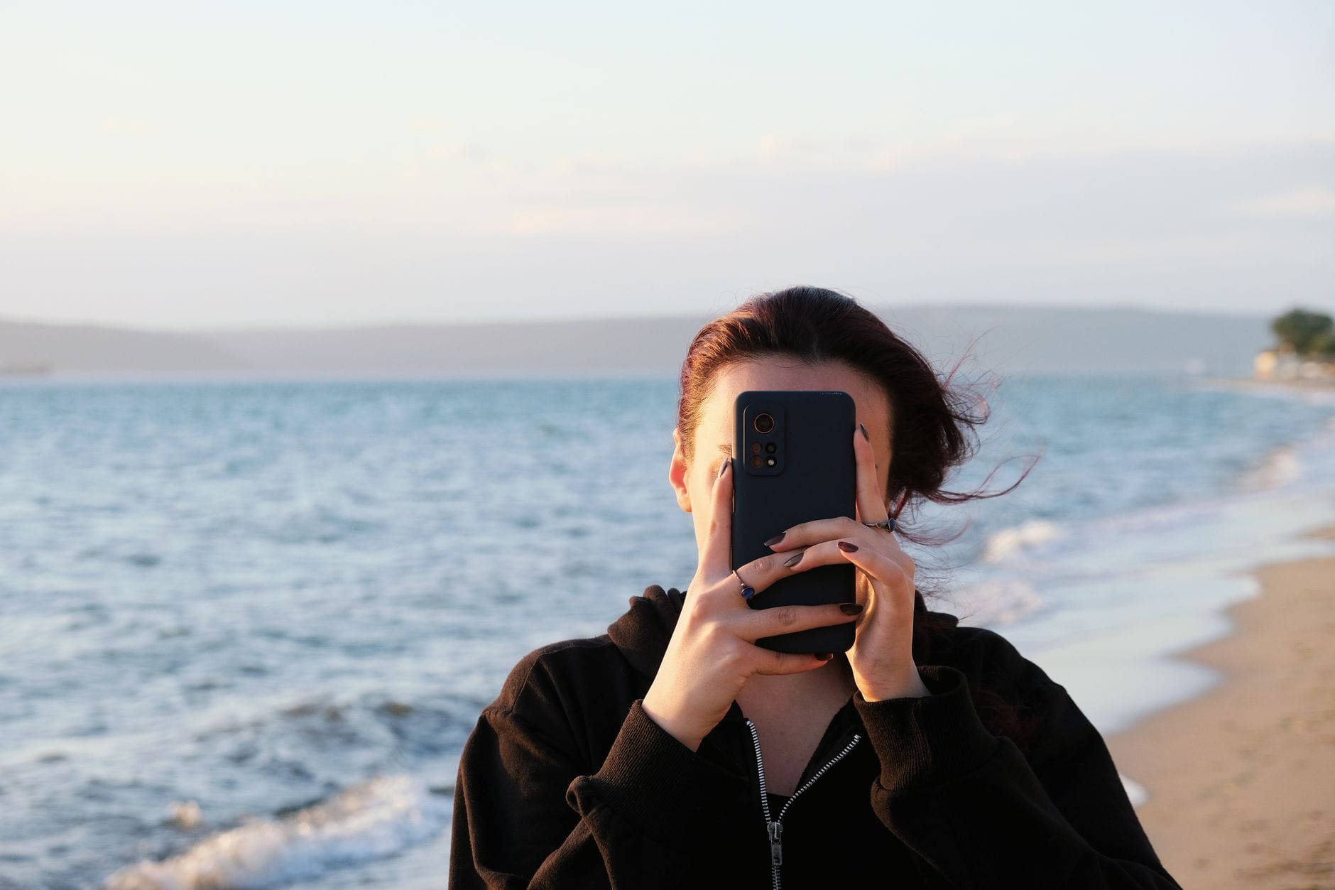 Kobieta fotografuje smartfonem widok plaży z morzem