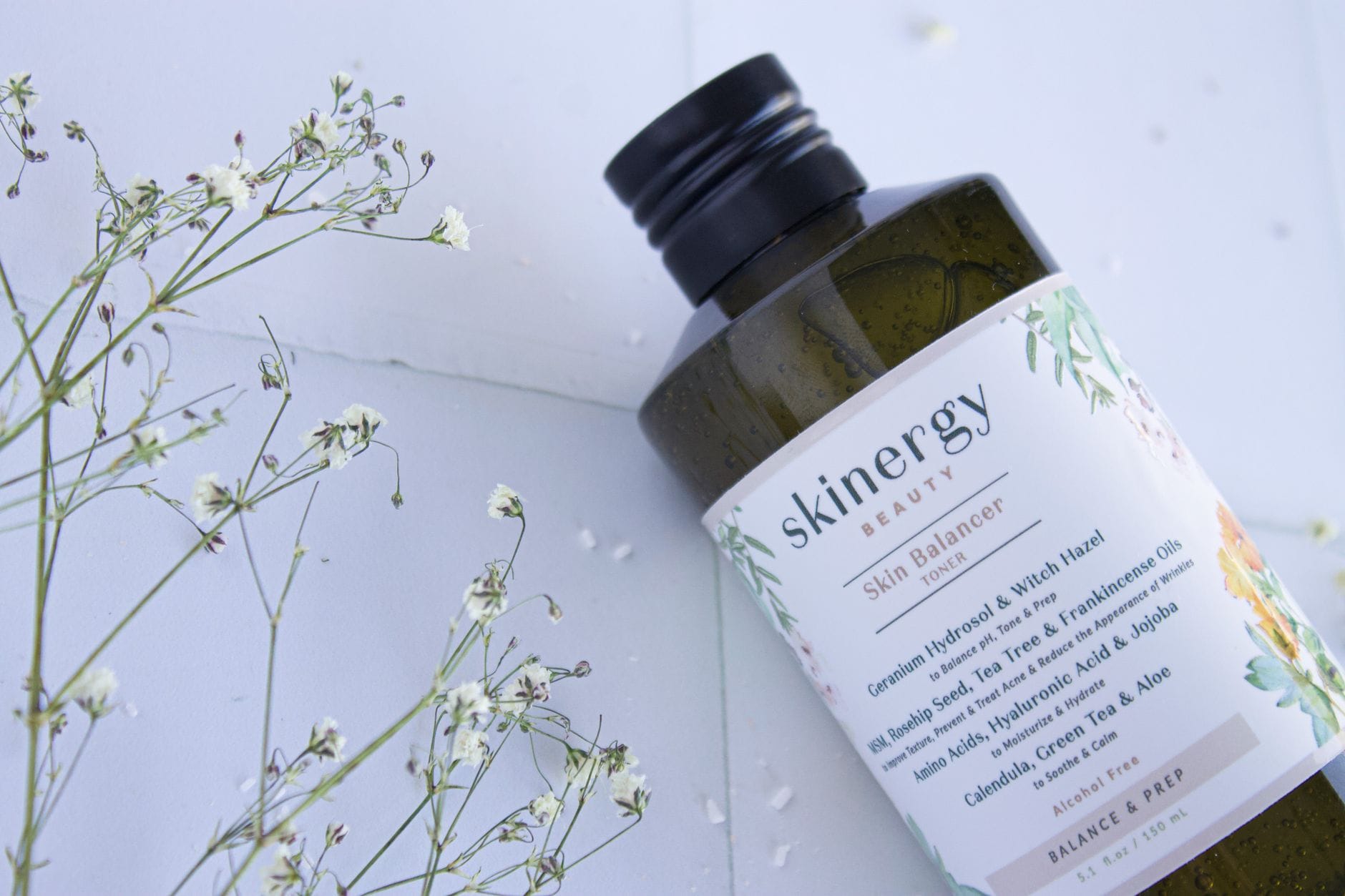 Zbliżenie na butelkę toniku Skinergy wśród delikatnych kwiatów